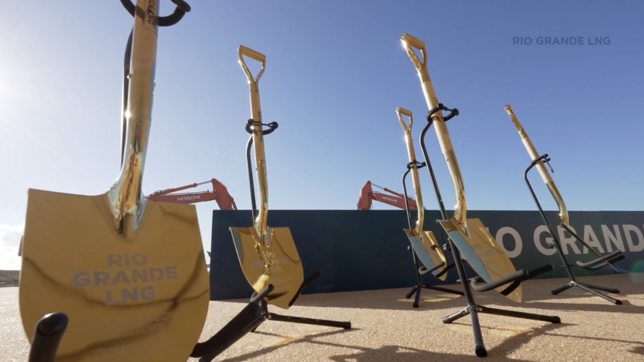 Branded ceremonial shovels lined up against the event wall in low sun