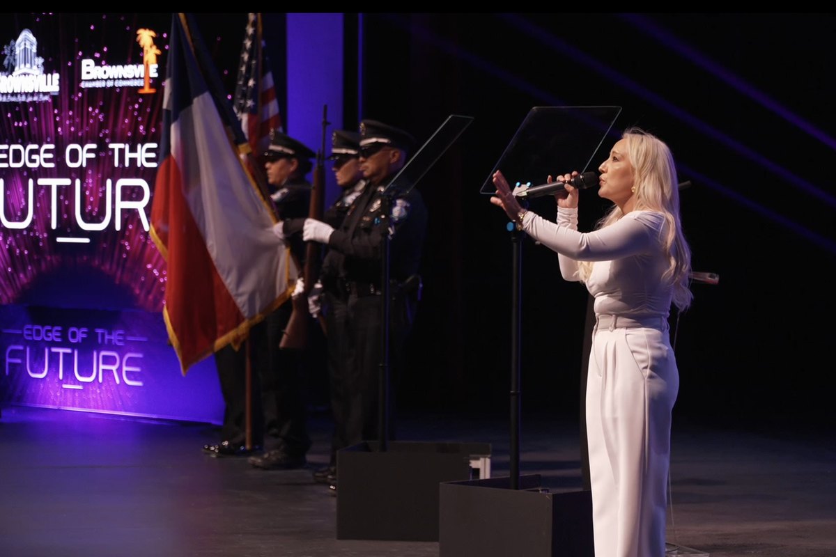The national anthem performed beside a color guard, with the event's neon title treatment on the screen behind