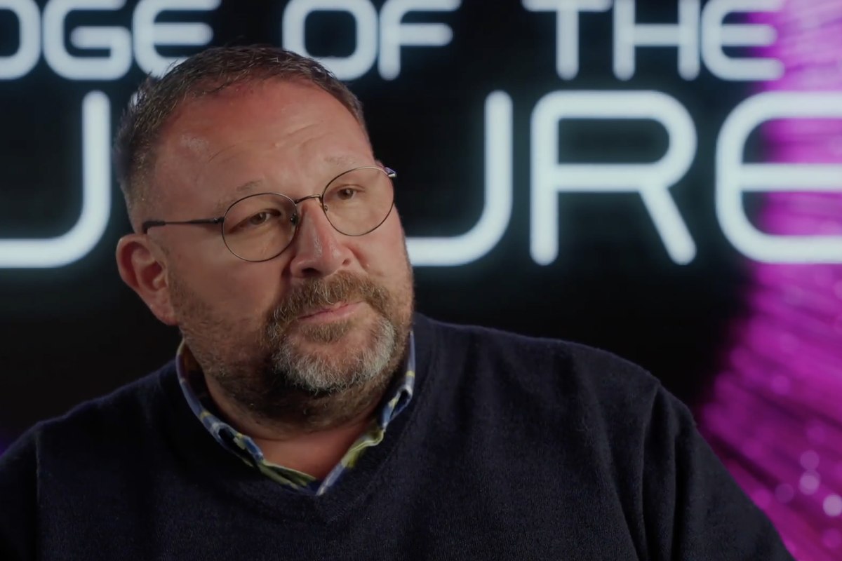 A lit interview subject filmed against the program's motion-graphic background