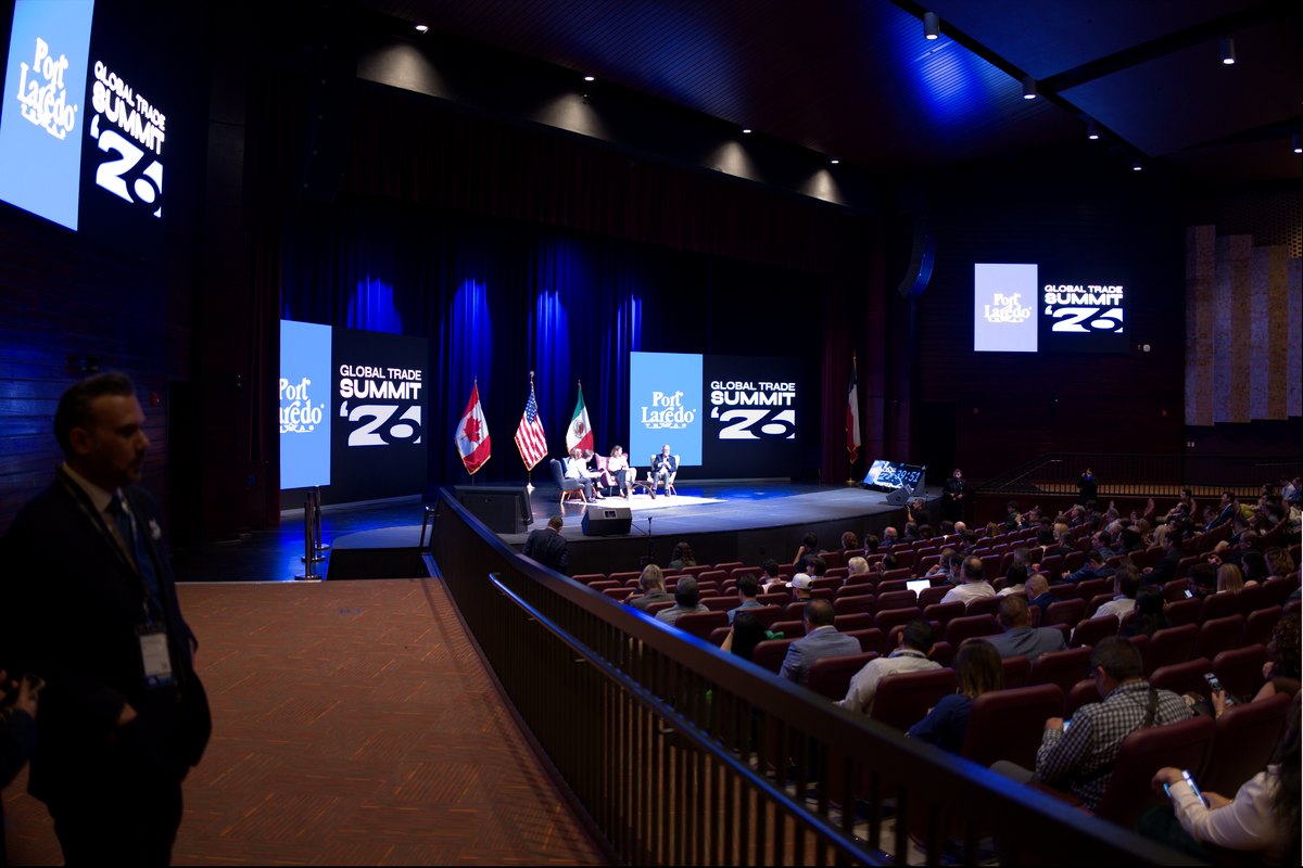 A trade summit conference stage with presentation screens